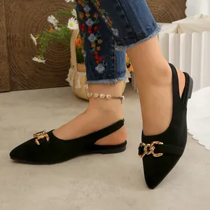 Close-up of black pointed-toe slingback flats with gold chain buckle detail on feet