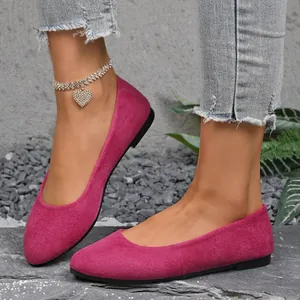 Primo piano di ballerine in camoscio fucsia indossate da una modella su superficie in pietra.