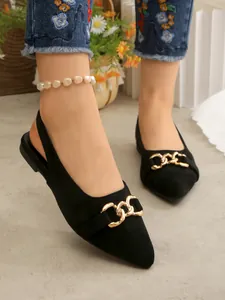 Detail of black suede pointed toe flats featuring a stylish gold chain buckle.