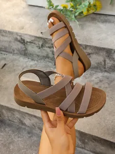 Detailed view of women's flat sandals featuring textured taupe elastic Roman straps