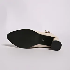 Detailed view of black non-slip sole and chunky block heel on beige rhinestone boot.