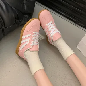 Baskets rétro de type entraîneur allemand pour femmes en rose et blanc, portées.