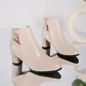 Detailed view of beige block heel ankle boots with elegant rhinestone V-shaped ornament