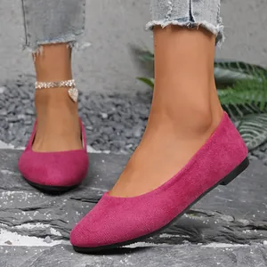 Dettaglio ravvicinato di eleganti ballerine a punta in camoscio fucsia su pietra