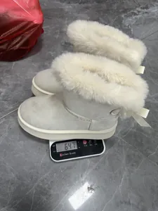 Macro detail showing a pair of beige fur-lined snow boots weighing 647g on a scale