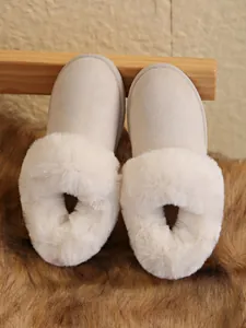 Close-up of beige snow boots with thick faux fur trim and warm fleece lining.