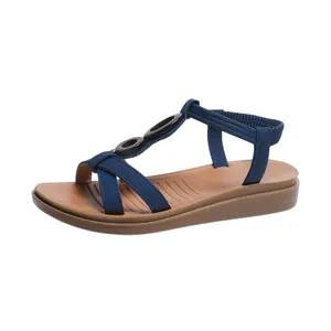 Detailed view of navy blue T-strap flat sandals with decorative rings and elastic strap