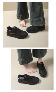 Detail view of black low-top platform sneakers worn with wide-leg denim jeans and bare feet