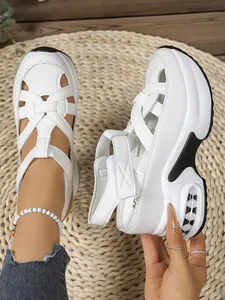 Close-up of white platform sandals with woven straps and Velcro closure on straw mat