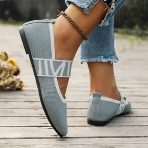 Close-up of stylish grey fly-knit flat shoes with elastic strap on a wooden deck