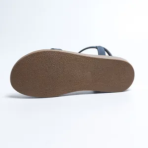 Detail view of the brown textured rubber outsole of the women's flat Roman sandal