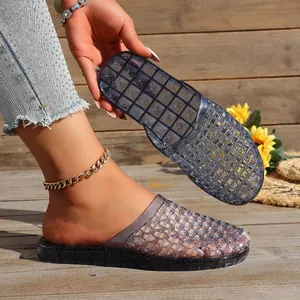 Detailed macro view of smoky grey hollow mesh jelly clogs on a rustic wooden deck.