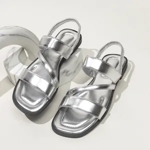 Detailansicht silberner Metallic-Flachsandale für Damen mit elastischen Kreuzgurten