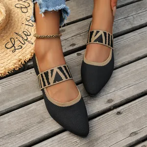 Close-up of breathable black fly-knit flats with patterned strap on wooden deck.