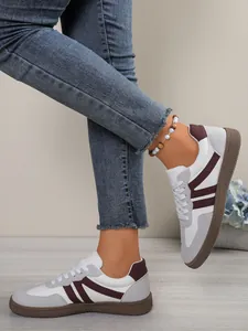 Close-up detail of women's color-block Gat Trainer sneakers paired with casual denim jeans.