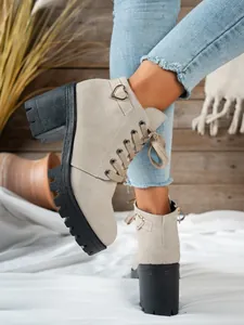 Dettaglio di stivaletti in camoscio beige con tacco largo e fibbia a forma di cuore