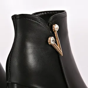 Detailed macro shot of black leather short boot featuring an elegant gold V-shaped rhinestone ornament