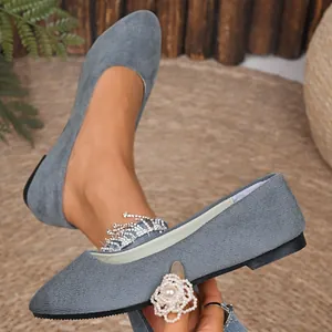 Dettaglio di scarpe basse a punta in camoscio grigio con texture morbida e design elegante.
