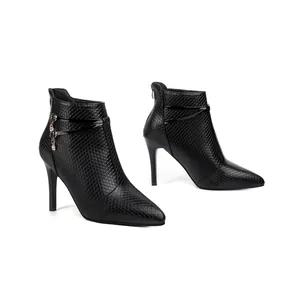 Close-up view of black stiletto ankle boots with textured pattern and rhinestone charm
