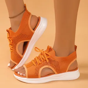 Detail view of orange fly-knit sports sandals with thick white soles for summer