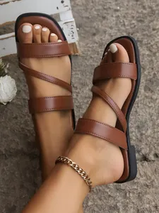 Detailed view of brown flat strappy sandals featuring a square toe and minimalist design