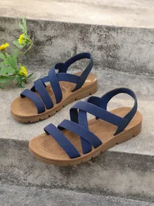 Detailed view of women's blue elastic strap Roman flat sandals on outdoor steps