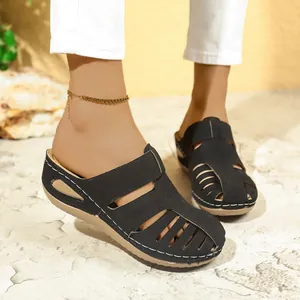 Nahaufnahme von schwarzen Damen-Mules mit Lochmuster und weißen Nähten für den Sommer.
