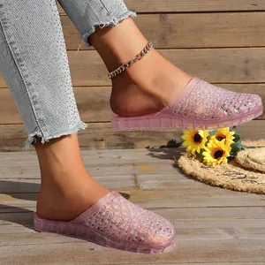Close-up of pink hollow breathable glitter jelly slippers on a wooden deck