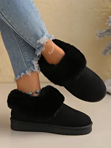 Close-up of warm women's black snow boots with plush faux fur trim and thick soles.