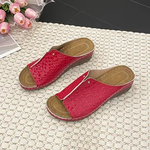 Detailansicht: rote Keilabsatz-Sandalen mit Krokodilmuster und weißen Nähten