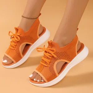 Close-up view of vibrant orange fly-knit sports sandals featuring thick white soles