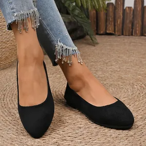 Vista dettagliata di eleganti ballerine nere in camoscio a punta su un tappeto di paglia