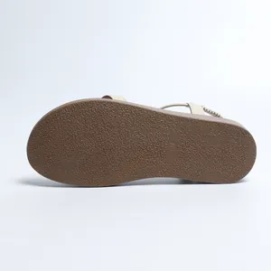 Detailed view of the textured non-slip brown sole of a comfortable women's flat sandal.