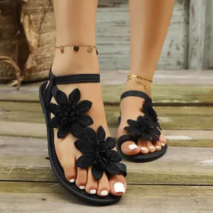 Close-up of black women's flat sandals featuring elegant lace flower applique and thong design.
