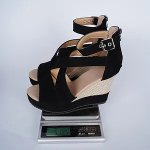 Detailed weight measurement of black suede wedge sandals on a digital scale for shipping