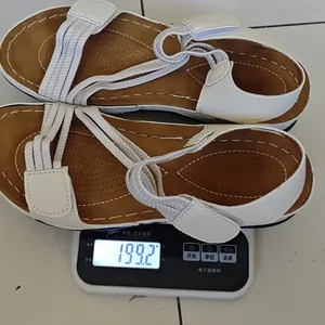 Close-up detail of lightweight white women's sandals being weighed at 199.2 grams