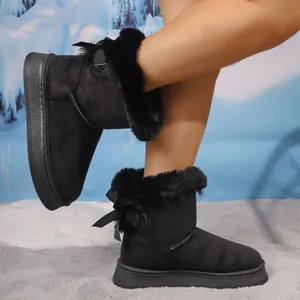 Close-up of black women's winter snow boots with fur trim and bow detail on thick sole