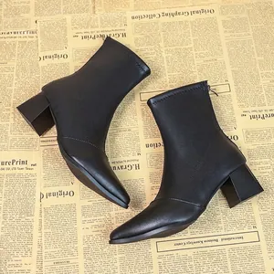 Elegante schwarze spitze Stiefeletten mit hohem Absatz für Damen auf Zeitungshintergrund