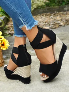Detail view of black suede wedge sandals featuring woven straw platform and back zipper