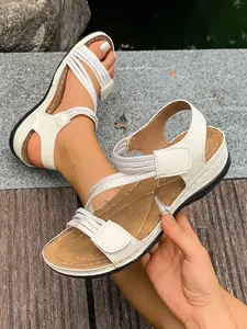 Close-up of women's white sporty flat sandals with elastic straps and Velcro closure