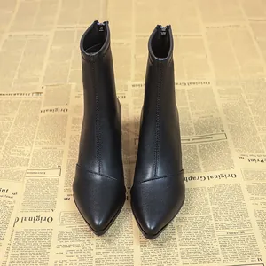 Nahaufnahme von eleganten schwarzen Stiefeletten mit spitzer Zehenpartie auf Zeitung