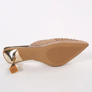 Bottom sole detail of a pointed-toe rose gold glitter pump with sculptural heel