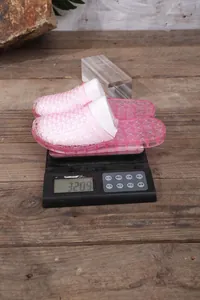 Macro view of lightweight pink hollow-out slippers being weighed on a digital scale