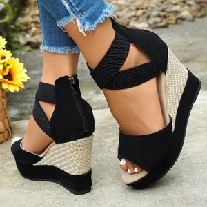 Close-up detail of black suede wedge sandals featuring woven platform and elastic ankle straps.