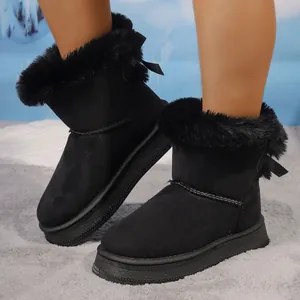 Close-up of black winter snow boots with plush trim and decorative bowknot details