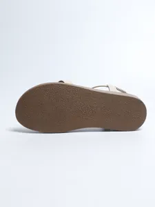 Bottom view of women's flat Roman sandal showing the textured brown rubber sole detail