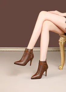 Close-up of brown pointed-toe stiletto boots with rhinestone charms and textured finish.