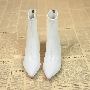 Elegante weiße Stiefeletten mit spitzer Kappe und hohem Absatz auf Vintage-Grund.