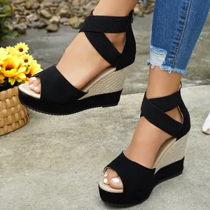Detailed side view of black suede platform wedge sandals with elastic cross straps