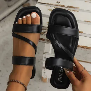 Detailed macro view of black square-toe flat sandals featuring multi-strap Roman style design.